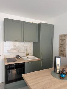 a kitchen with green cabinets and a sink at Victoria Palace T2 de 50m2 in Menton