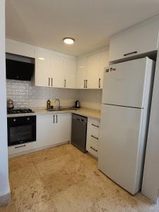 a kitchen with white cabinets and a white refrigerator at Ilya Apart 1 in Bodrum City