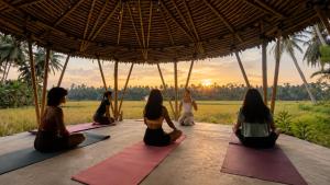 Eine Gruppe von Frauen sitzt unter einer Hütte bei einer Yogastunde. in der Unterkunft Mahati in Cijulang Nusawiru Airport
