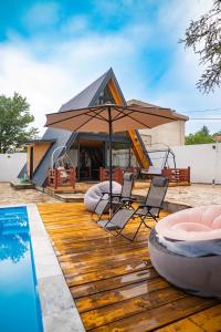 Eine Terrasse mit Stühlen und einem Sonnenschirm neben einem Pool in der Unterkunft Vila Markizo in Barajevo