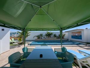 a green tent with a table and chairs and a pool at Villa SUN SQUARE DJERBA in Awlād ‘Umar
