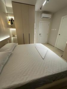 a large white bed in a room with a door at Ionian Rooms in Vlorë
