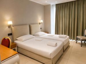 ein Hotelzimmer mit einem großen weißen Bett und einem Schreibtisch in der Unterkunft Hotel Iliana in Filippiada + 46 Fotos