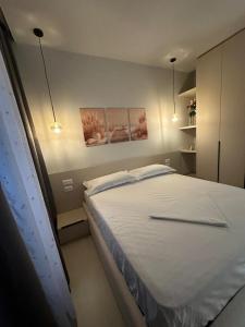 a bedroom with a large white bed with two lights at Ionian Rooms in Vlorë