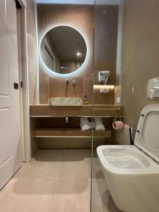 a bathroom with a sink and a mirror and a toilet at Ionian Rooms in Vlorë