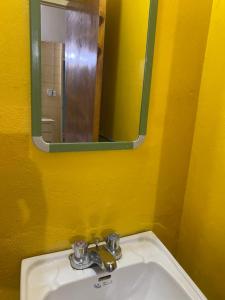 a yellow bathroom with a sink and a mirror at Rooms on the 7 Mile in Negril +12 photos
