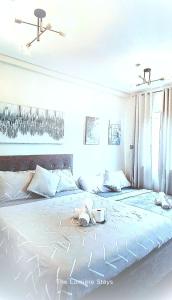 a bedroom with a large white bed with two phones on it at The Lumière Stays Cozy Mallside Boutique Haven in Trece Martires +17 photos