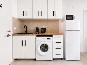 a white kitchen with a washing machine and a refrigerator at Sanchis Studios in Alicante