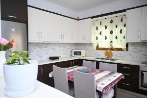a kitchen with white cabinets and a table with chairs at Villa Nertili 1 in (( Kalive Gjoka ))