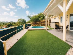 a backyard with a swimming pool and a white pergola at Les Cocons des Alizés in Sainte-Anne