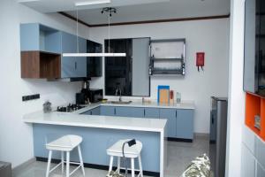 a kitchen with blue cabinets and two stools at Juney Villas Zanzibar in Zanzibar City