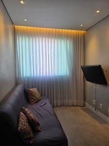 a living room with a couch and a large window at Apartamento 2 Quartos Moderno in Belo Horizonte +2 photos