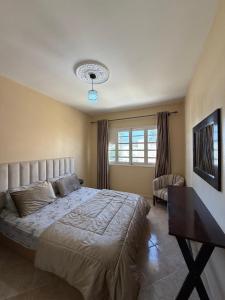 a bedroom with a large bed and a window at Villa le Palmier in Saïdia