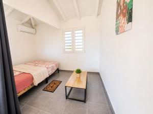 a bedroom with a bed and a table and a window at Les Cocons des Alizés in Sainte-Anne