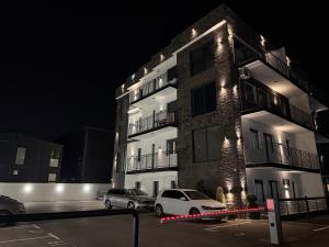 two cars parked in front of a building at night at El Paso Grande in Ledine