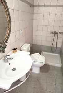 a bathroom with a sink and a toilet and a mirror at Studios Poulati in Artemonas