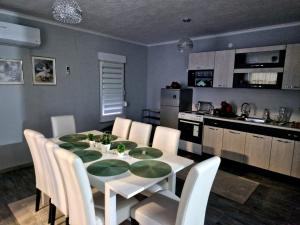 a dining room table with white chairs and a kitchen at Villa Martar in Mostar