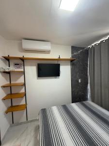 a bedroom with a bed and a flat screen tv at Flat do Lucca 02 - Piscina - 50m da Praia - Até 10 Pessoas in Tamandaré