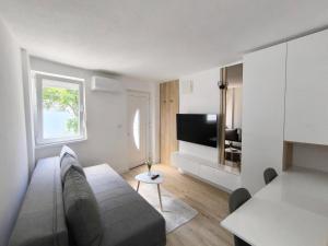 a living room with a couch and a television at El Higo Apartments in Mostar