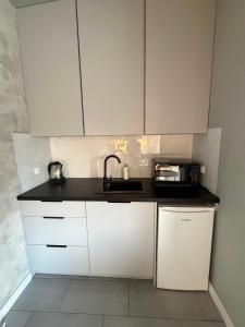 a kitchen with white cabinets and a sink at Domki za Wyspą in Chmielów
