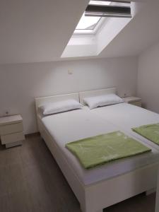 a bedroom with a white bed and a skylight at Apartmani Deluxe in Jasenice