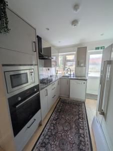 a kitchen with white cabinets and a black stove top oven at 6 bedroom house Trochetia in Crawley