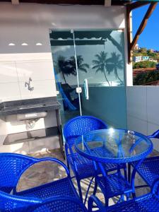 a patio with blue chairs and a glass table at Flat Galemares in Maragogi