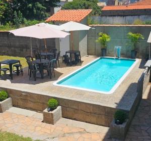 a swimming pool with tables and chairs and an umbrella at Pousada Barão Real in São Lourenço
