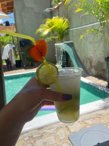 a hand holding a drink with a slice of lime at Pousada Barão Real in São Lourenço