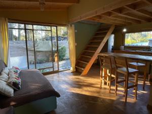 a living room with a staircase and a table and chairs at Cabaña en Buchupureo in Tiuquilemu