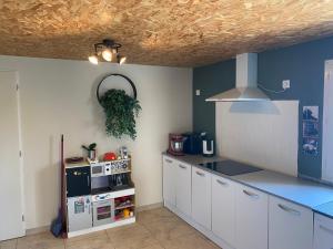 a kitchen with white cabinets and a blue wall at Le Cocon de Réals in Murviel