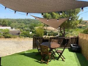 a patio with a table and chairs on the grass at Le Cocon de Réals in Murviel