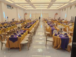 a large banquet hall with tables with purple and yellow table settings at Bintumani in Freetown +104 photos