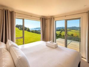 a bedroom with a large white bed and a large window at Overview - Stay Waiheke in Ostend +16 photos