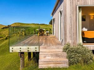 a glass house with a wooden deck and a table at Overview - Stay Waiheke in Ostend
