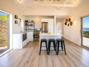 a kitchen with a counter and two stools in it at Overview - Stay Waiheke in Ostend