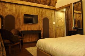 ein Schlafzimmer mit einem Bett und einem Fernseher an der Wand in der Unterkunft CEDARS Resorts - Doodhpathri Kashmir in Rengazabal