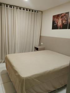 a bedroom with a bed in a room with curtains at Flat em Gravatá -Villa Monte Castelo - 2 quartos- Ao Lado da Área de Lazer e das piscinas in Gravatá
