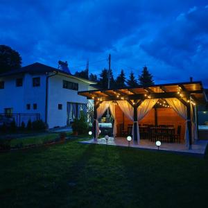 a wooden pavilion with lights in a yard at night at Serbeca in Broşteni