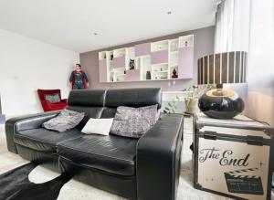 a living room with a black leather couch at KeschtaLoft - Gîte classé 4 étoiles in Châtenois