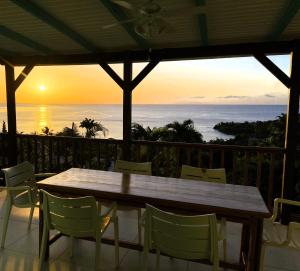 a table and chairs on a balcony with a sunset at Espace Harmonie Deshaies - Vue Mer & Piscine Panoramique in Deshaies