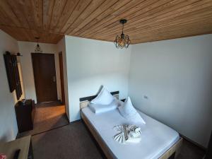 a bedroom with a white bed with a wooden ceiling at Serbeca in Broşteni