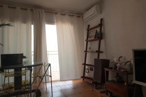 a living room with a television and a table and a window at Comfortable and Elegant Seafront Apartment in Faro de Cullera