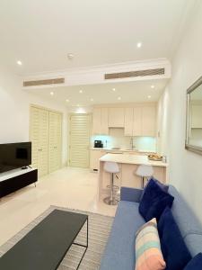 a living room with a blue couch and a kitchen at Porto Marina Residence in Tivat