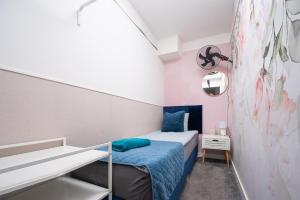 a small bedroom with a blue bed and a staircase at S-HE Space - Budget Micro Rooms Kraków in Krakow