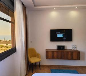 a room with a tv and a chair and a window at DAR-VIDA Guesthouse in Imsouane