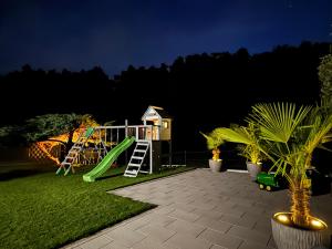 a playground with a green slide in a yard at night at Familienfreundliche Ferienwohnung mit Garten & Spielplatz nahe Nürnberg Playmobil FunPark in Veitsbronn