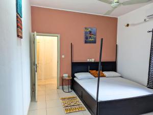 a bedroom with two beds and a door to a bathroom at Petit Cocon de Ouidah - Chambre Cosy Climatisée - Plage a 10 min - Salon, Cuisine et balcon in Ouidah