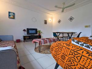 a living room with two beds and a television at Petit Cocon de Ouidah - Chambre Cosy Climatisée - Plage a 10 min - Salon, Cuisine et balcon in Ouidah