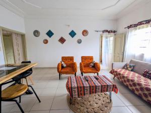 a living room with a couch and chairs and a table at Petit Cocon de Ouidah - Chambre Cosy Climatisée - Plage a 10 min - Salon, Cuisine et balcon in Ouidah